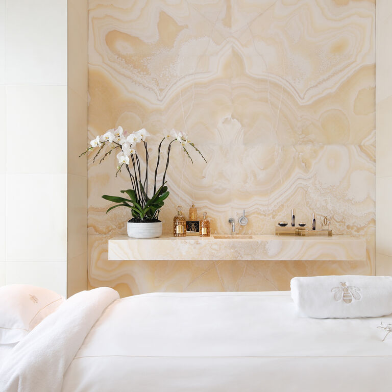 A GUERLAIN SPA ROOM WITH BEIGE UNDERTONES AND AN ORCHID AND GUERLAIN PRODUCTS IN THE BACKGROUND